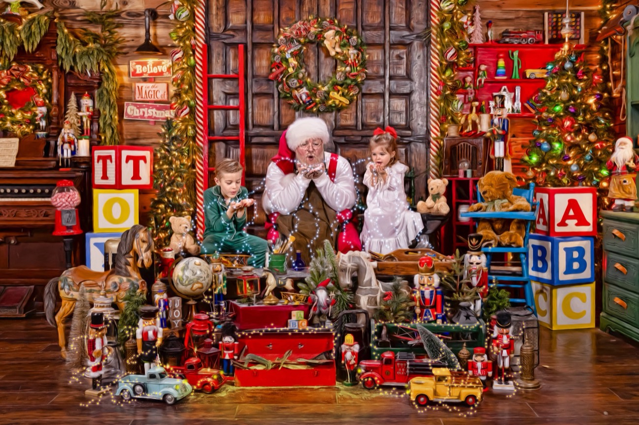 Commissioned art: Santa, hands to his cheeks in delight, with two children among the toys in his workshop